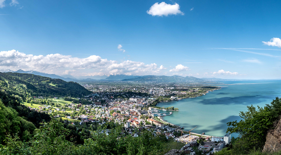 Auf dem Bild ist ein Panorama von Bregenz von oben zu sehen. Der Himmel ist blau. 