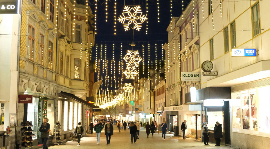 Das Foto zeigt die abendliche Weihnachtsbeleuchtung in der Bregenzer Kaiserstraße sowie Menschen, die durch die Straße bummeln.