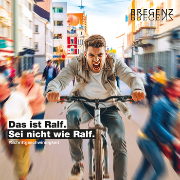 Da Bild zeigt ein computergeneriertes Bild, auf dem ein junger Mann viel zu schnell und aggressiv durch die Bregenzer Rathausstraße fährt. Darunter ist zu lesen "Das ist Ralf. Sei nicht wie Ralf. #Schrittgeschwindigkeit"