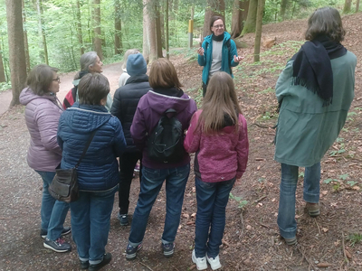 Auf dem Foto sieht man Karin Müller Vögel im Wald mit sieben weiteren Damen bei einem Waldspaziergang. 
