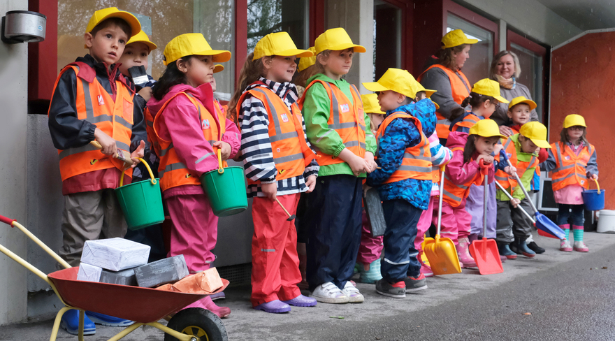 Diese Abbildung zeigt Kindergartenkinder, welche Warnwesten und gelbe Schildkappen tragen.