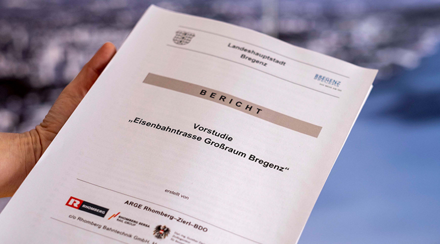 Hier wird ein Bericht mit dem Titel "Vorstudie - Eisenbahnstraße Großraum Bregenz" in der Hand gehalten.