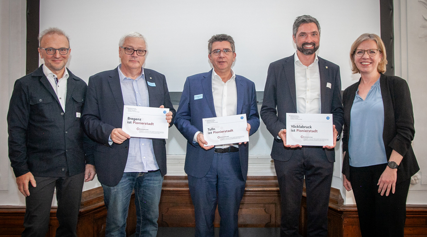 Das Foto zeigt u. a. Stadtrat Heribert Hehle aus Bregenz mit Bundesministerin Leonore Gewessler bei der Übergabe der Plakette. 