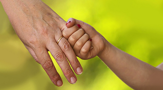 Diese Abbildung zeigt die Hand einer Frau. Ein Kind hält diese an zwei Fingern fest.