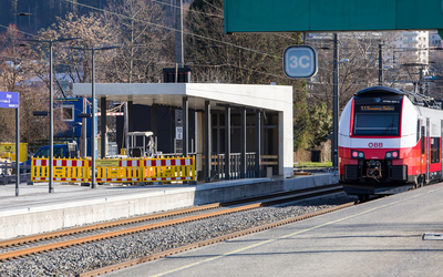 Auf dem Foto sieht man einen Bahnsteig während der Bauarbeiten mit einer gelben Absperrung vorne. und einem roten Zug rechts.