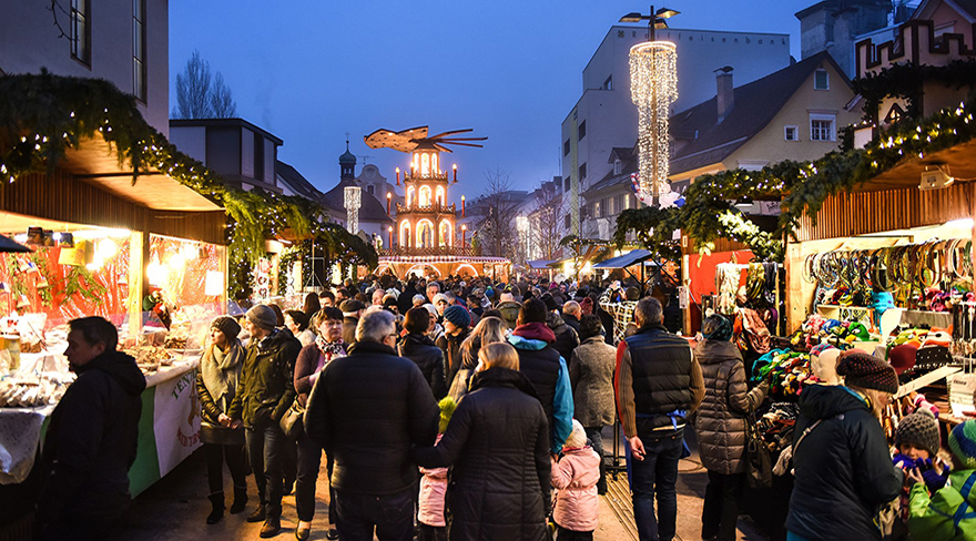 Diese Abbildung zeigt Besucher:innen des Bregenzer Weihnachtsmarktes am Abend.