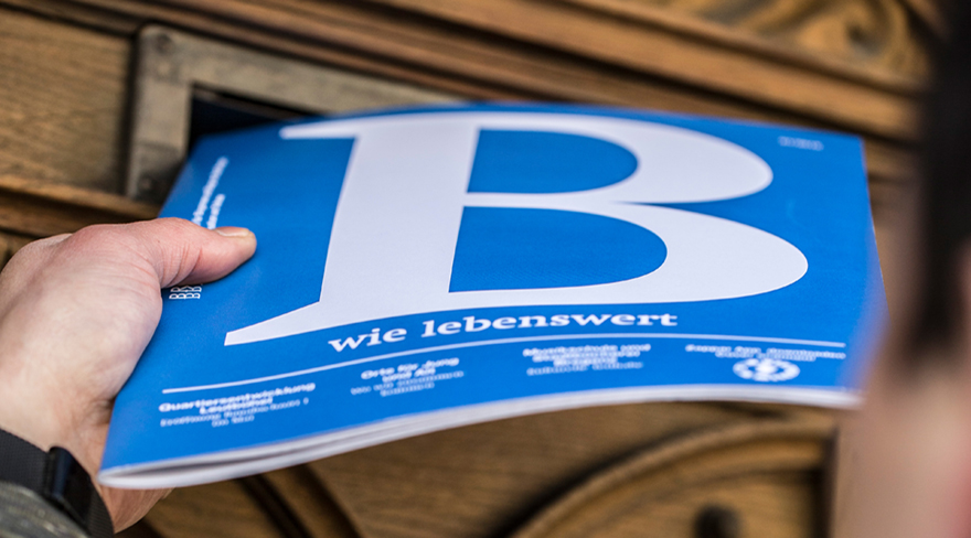 Diese Abbildung zeigt einen Briefträger, welcher das Magazin B in einen Briefkasten wirft. Auf dem blauen Cover ist ein großes "B" abgebildet.