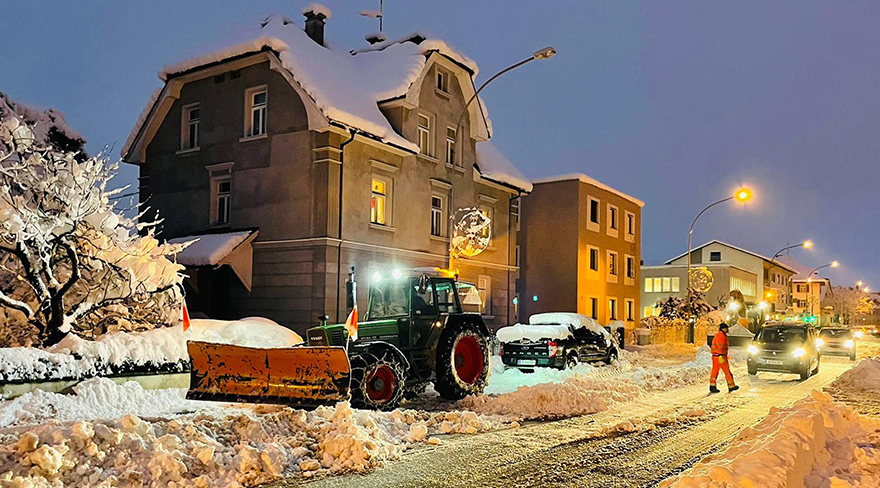 Hier ist die Schneeräumung einer Straße mit Hilfe eines Traktors abgebildet.