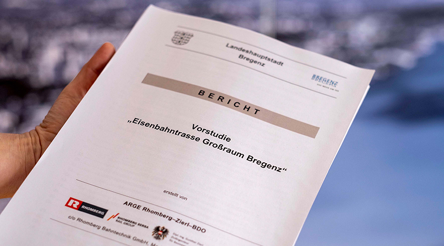 Hier wird ein Bericht mit dem Titel "Vorstudie - Eisenbahnstraße Großraum Bregenz" in der Hand gehalten.